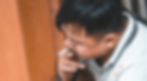 Man with black hair seen from above, sitting and smoking a cigarette