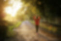 Woman seen from the back walking on a countryside road at the golden hour