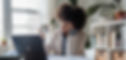 Woman at her desk in a home office looking depressed and overwhelmed in front of her laptop